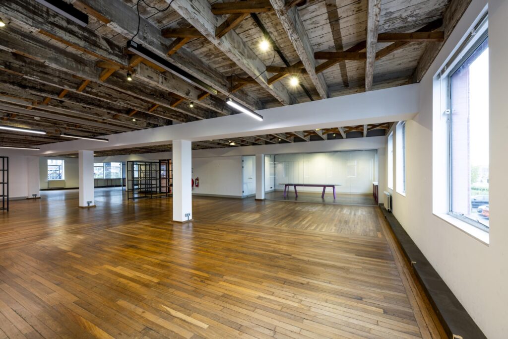 Licht en ruim kantoorinterieur aan de De Ruijterkade met houten vloer en een industrieel plafond.